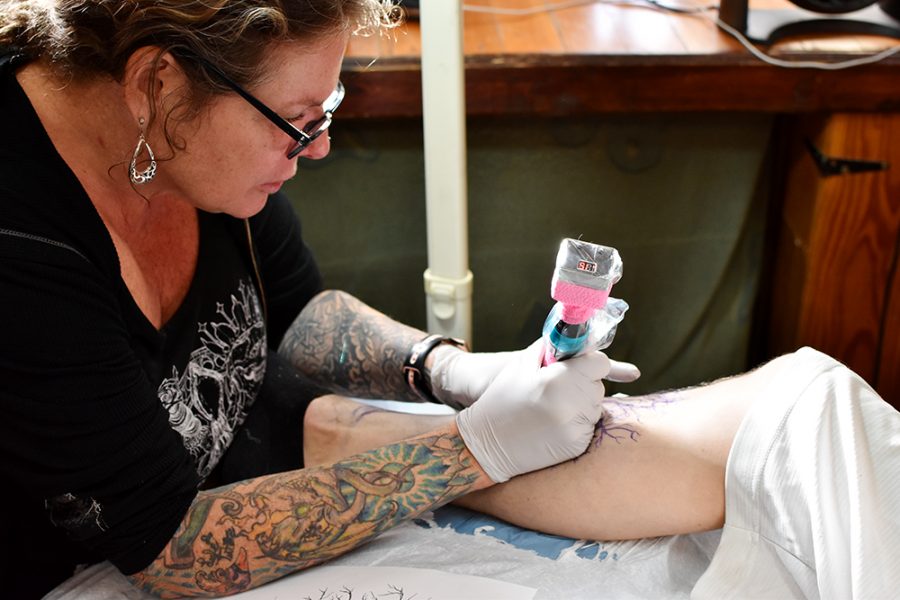 Telisa Swan, owner and tattoo artist at Swan Family Ink, tattoos an oak tree on customer Jordan Shulls shin Thursday afternoon at Swan Family Ink in Moscow.
