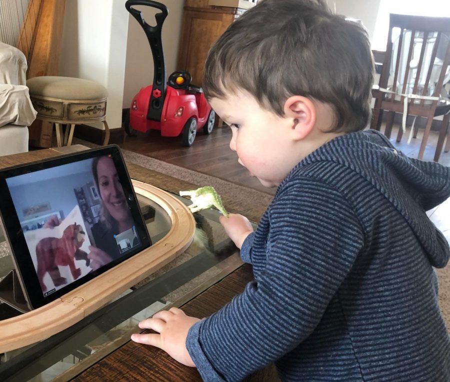 Sage, a toddler who attends WSUs Children Center, is listening to his teacher Jonnie read a book over Zoom. 