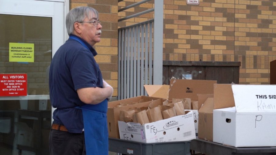 Richard Carbonneau, Pullman High School food service employee, stands in front of grab-and-go lunches. The meals are available for pick-up at Jefferson Elementary School. 
