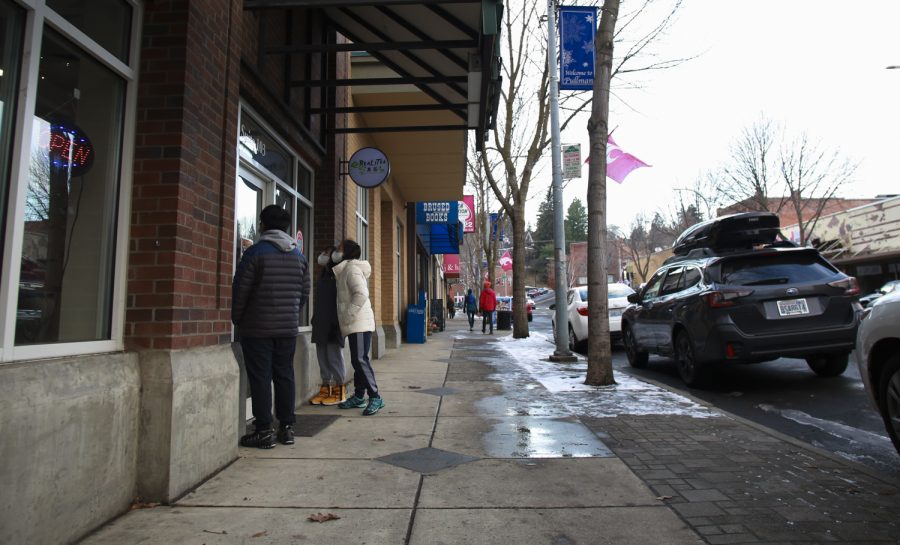 Pullman resident Amber Nguyen peers into RealiTea as she and her children, Sammie and Ben, wait their turn to enter and order their meals Wednesday afternoon on Main Street in Pullman. 