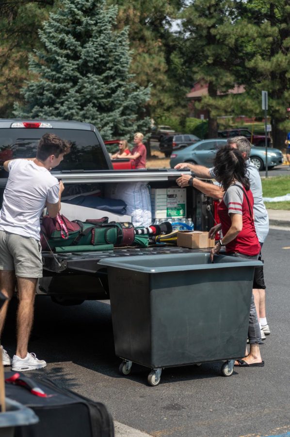 Ethan Henderson (left) and his parents (right) unload his belongings from their truck outside of Streit Hall.
