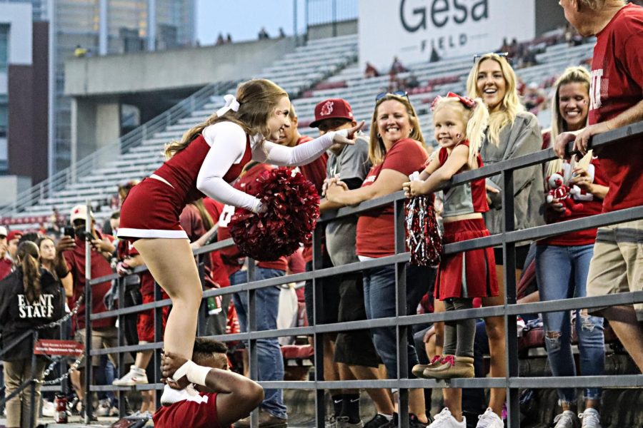 A member of the Washington State University cheer team greets a fan at Martin Stadium in Pullman, Wash., Saturday, Sept. 4, 2021.