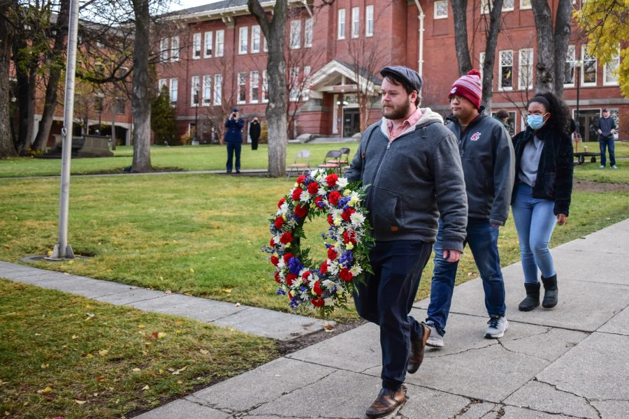 Corey Gardner, Student Veterans Committee chair, Bryan Chang, Student Veterans Committee member, and Jenna Fitzgerald, ASWSU director of inclusion, diversity, and veterans affairs, carry a wreath past the flagpole in front of Bryan Hall.