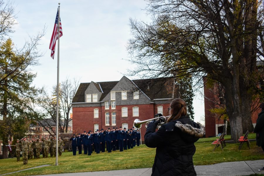Amber Vosk, senior music education major, plays taps on the trumpet while Army and Air Force ROTC cadets salute the American flag. 