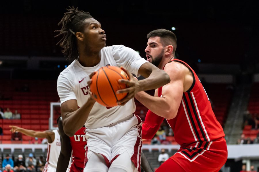 WSU forward Efe Abogidi (left) looks for the hoop while Utah forward Dusan Mahorcic (right) fights for the ball during the first half of an NCAA collegiate basketball game, Wednesday, Jan. 26, in Beasley Coliseum.