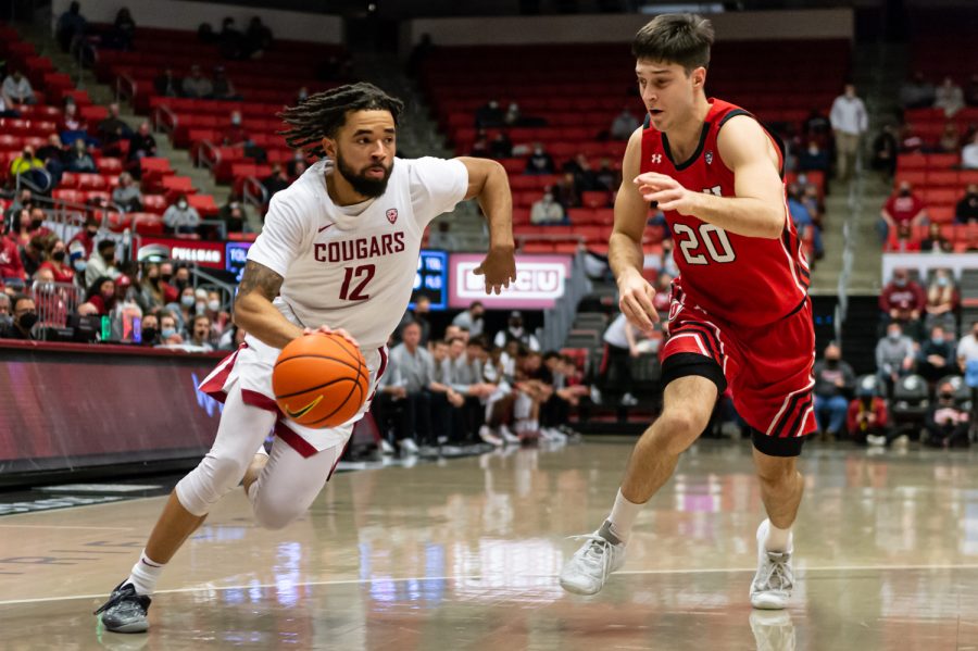 WSU guard Michael Flowers (12) dribbles past Utah guard Lazar Stefanovic (20) during the first half of an NCAA collegiate basketball game, Wednesday, Jan. 26, in Beasley Coliseum.