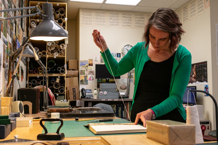 Linnea Rash, WSU Conservator Museum Specialist, mends Washington State College staff bulletins on April 19 in her conservation lab.