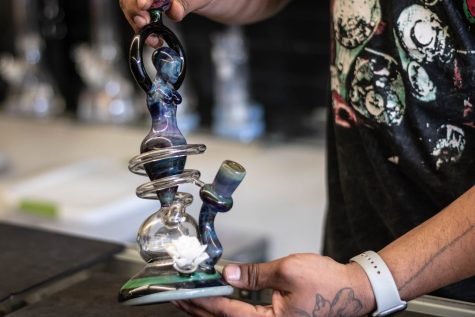Glassphemy clerk Felix Alatorre displays a bong crafted by Mike Porter, featuring one of his signature glass coils.