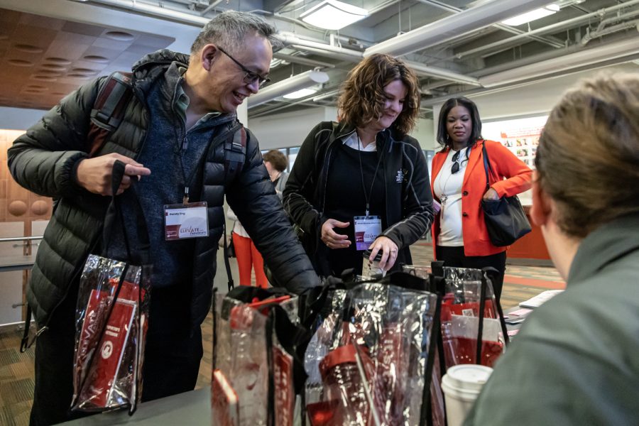 Atendees Randy Egg and Nicole Neumann grab gift bags off of the front desk at Murrow Symposium 46, April 5.