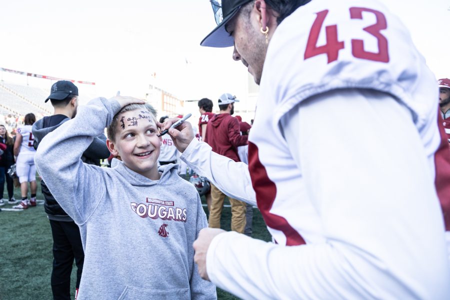 WSU defensive back Jacob Skobis signs the cheek of a young WSU fan after the 2022 Spring Game, April 23, at Martin Stadium.