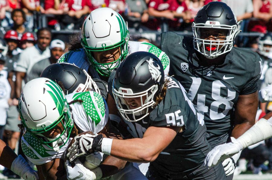 WSU+defenders+tackle+an+Oregon+player+during+an+NCAA+college+football+game%2C+Sep.+24.