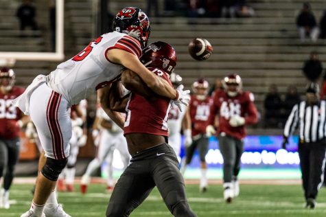 Utah tight end Dalton Kincaid attempts to catch the ball by jumping over WSU defensive back Jordan Lee during an NCAA football match, Oct. 27.