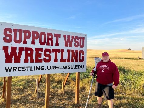 Phil Burnett, coach of WSU wrestling poses next to the support WSU wrestling sign along Washington Highway 26.
