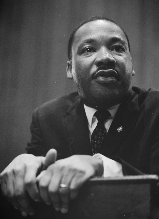 Martin Luther King leaning on a lectern, 1964. 