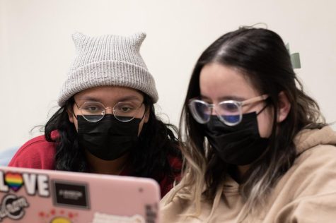 Two students studying together, wearing masks. 