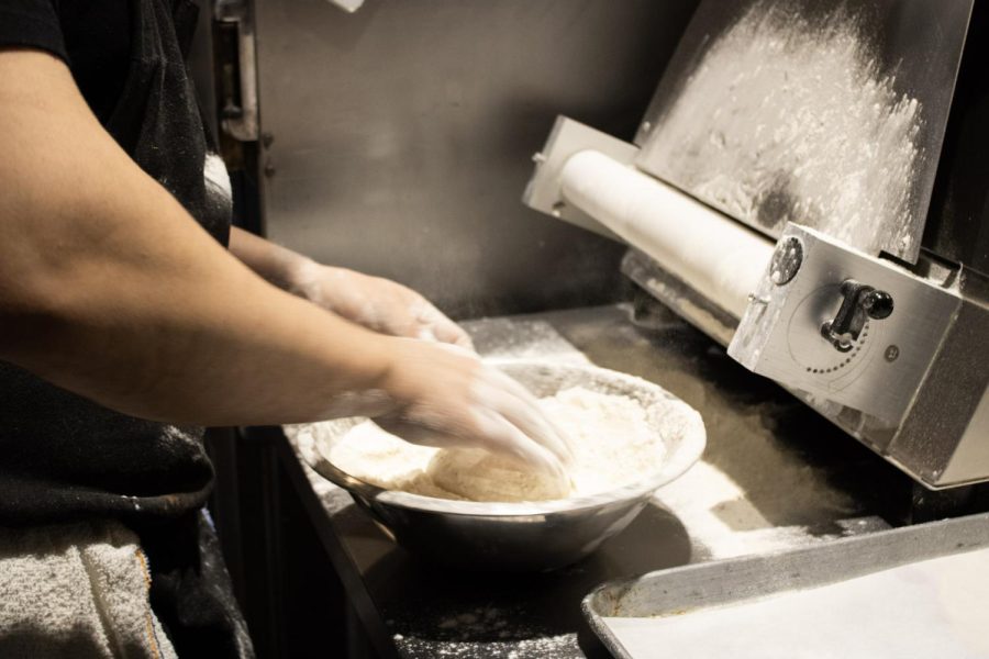 A cook pulls pita dough out of a dough-flattening machine at The Black Cypress Feb. 6.