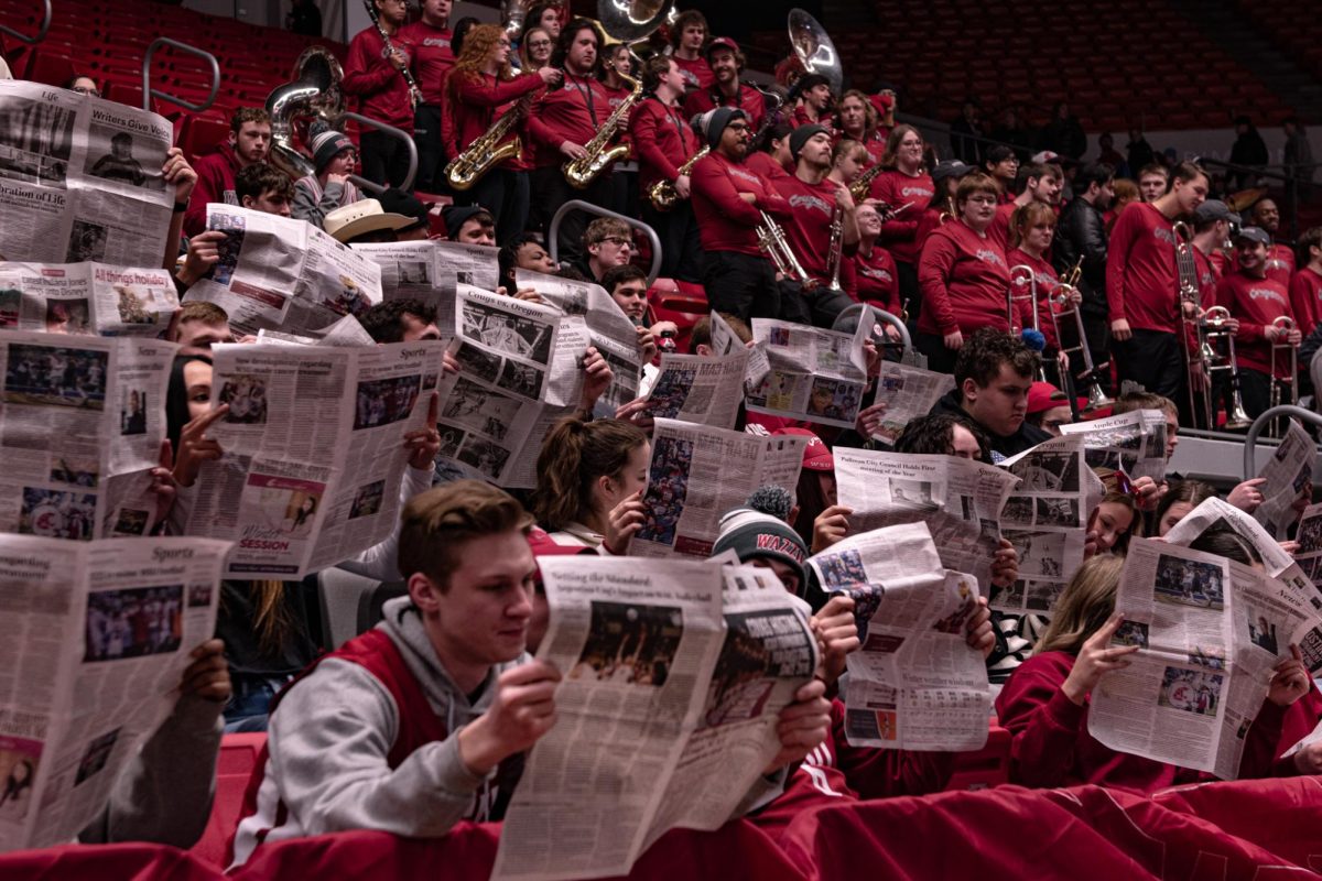 The student section reads copies of The Daily Evergreen as the starters of Arizona are announced, Jan. 13, in Pullman, Wash. 