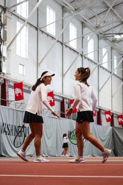 WSU tennis players Eva Alvarez Sande and Elyse Tse high-five during an NCAA doubles match against Eastern Washington, Jan. 20, 2024, in Pullman, Wash.