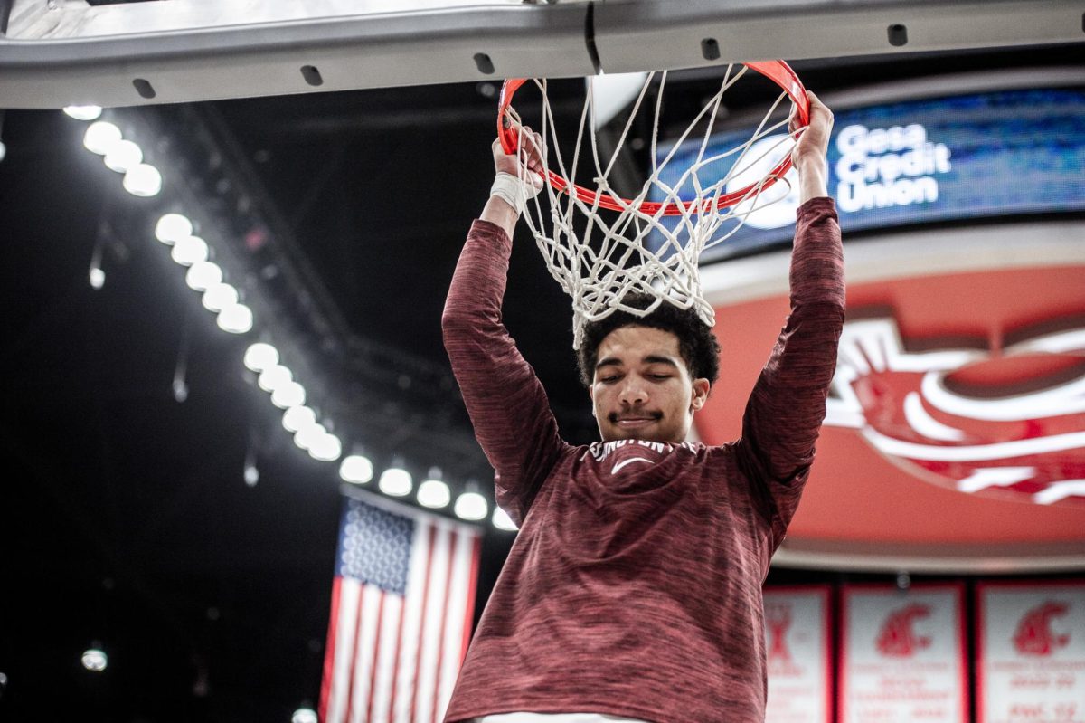 Myles Rice hangs on the rim after the anthem plays, Feb. 15, in Pullman, Wash.