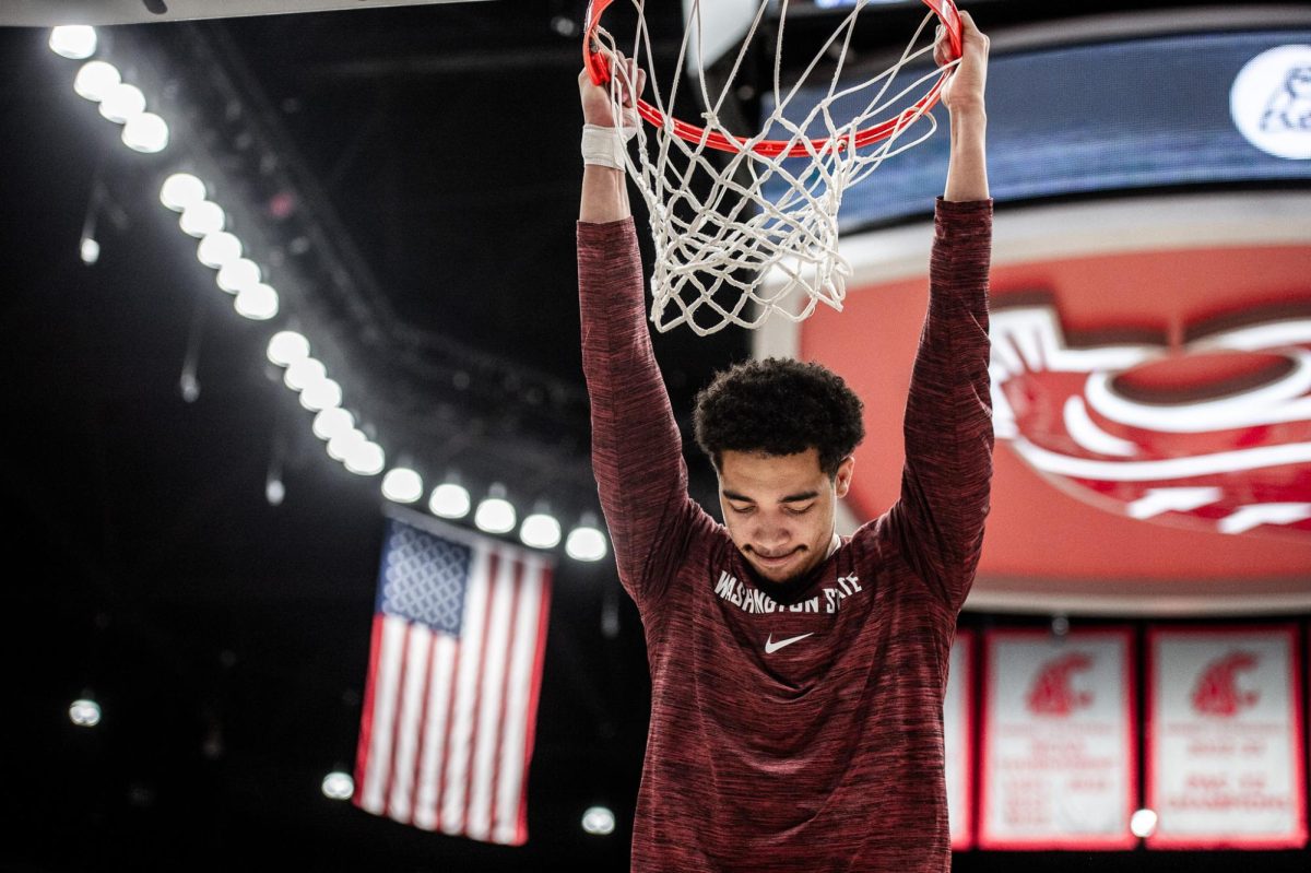 Myles Rice hangs on the rim after the anthem plays, Feb. 15, in Pullman, Wash.