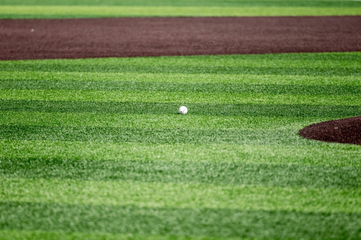 A baseball rests on the turf awaiting for first pitch, March 20, in Pullman, Wash. 
