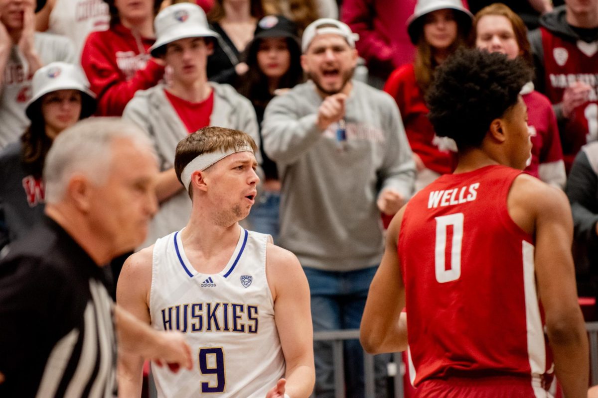 UW graduate guard Paul Mulcahy protests a call while WSU junior forward Jaylen Wells and Coug fans look on during an NCAA basketball game between WSU mens basketball and UW, March 7 in Pullman, Wash.