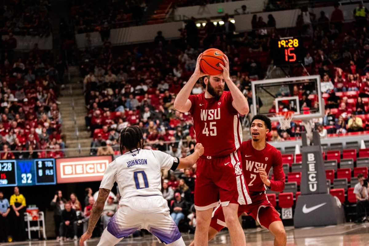 Oscar Cluff tries to pass the ball to Myles Rice in WSUs 74-68 loss to UW, March 7 in Pullman, Wash.