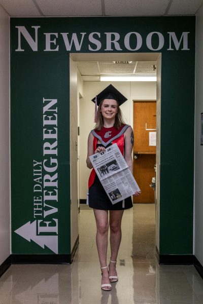 Alexandria Osborne in front of The Daily Evergreen door in graduation regalia on April 20, 2024 in Pullman, Wash.