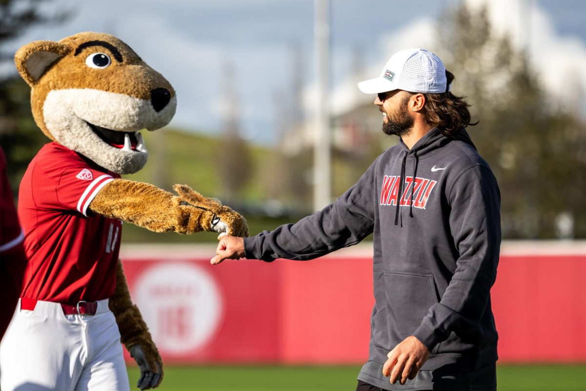 Former WSU QB Gardner Minshew fist bumps Butch after throwing out the ceremonial first pitch, April 26, in Pullman, Wash. 