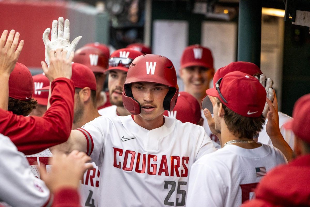 Casen Taggart high-fives teammates in the dugout after scoring the Cougs first run, April 12, in Pullman, Wash. 