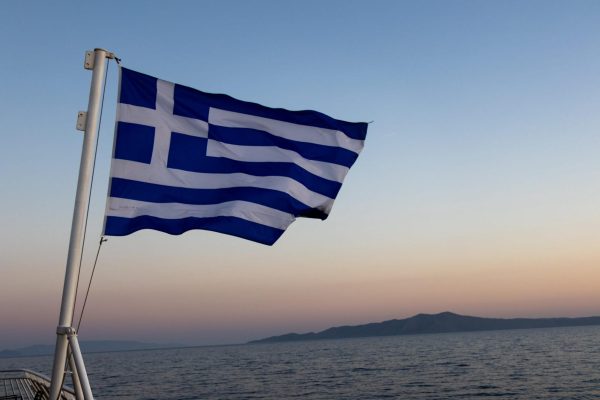 The Greek flag waves off the edge of a boat traveling between islands, May 24, in Greece. 