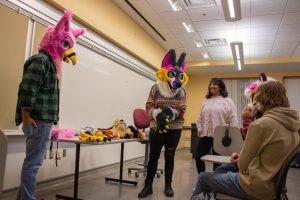 Members of the Furry Club try on some of the fursuit heads and paws at their meeting Tuesday