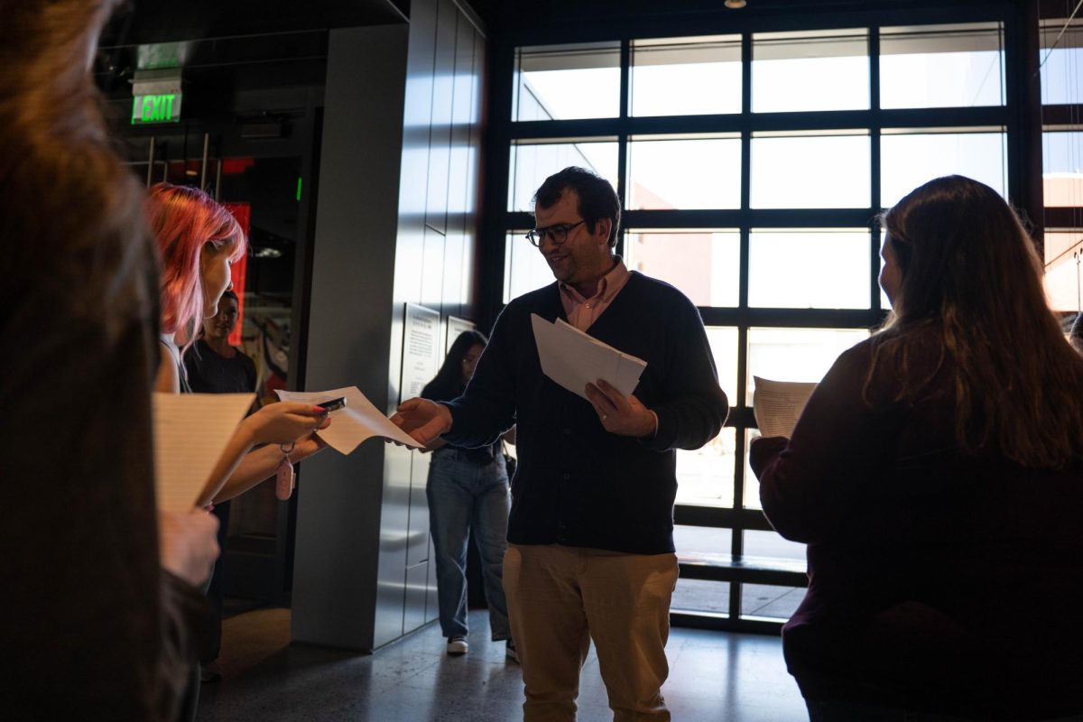 Washington State University Professor Colin Criss hands out copies of poems before a Community Perspectives Exhibitions Tour at the Jordan Schnitzer Museum of Art on Thursday, Oct. 9. 