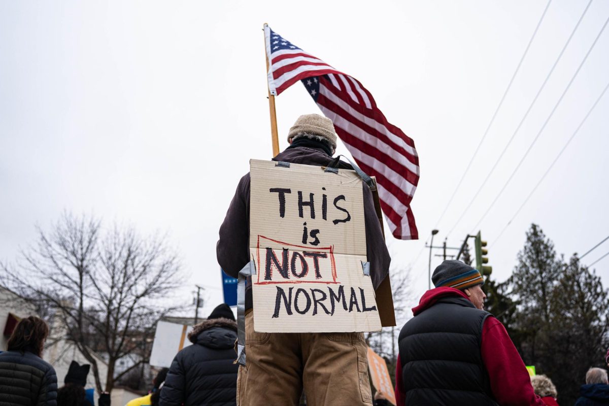 Anti-ICE protesters wave signs as cars pass by Cougar Plaza in downtown Pullman on Tuesday, Jan 20. 