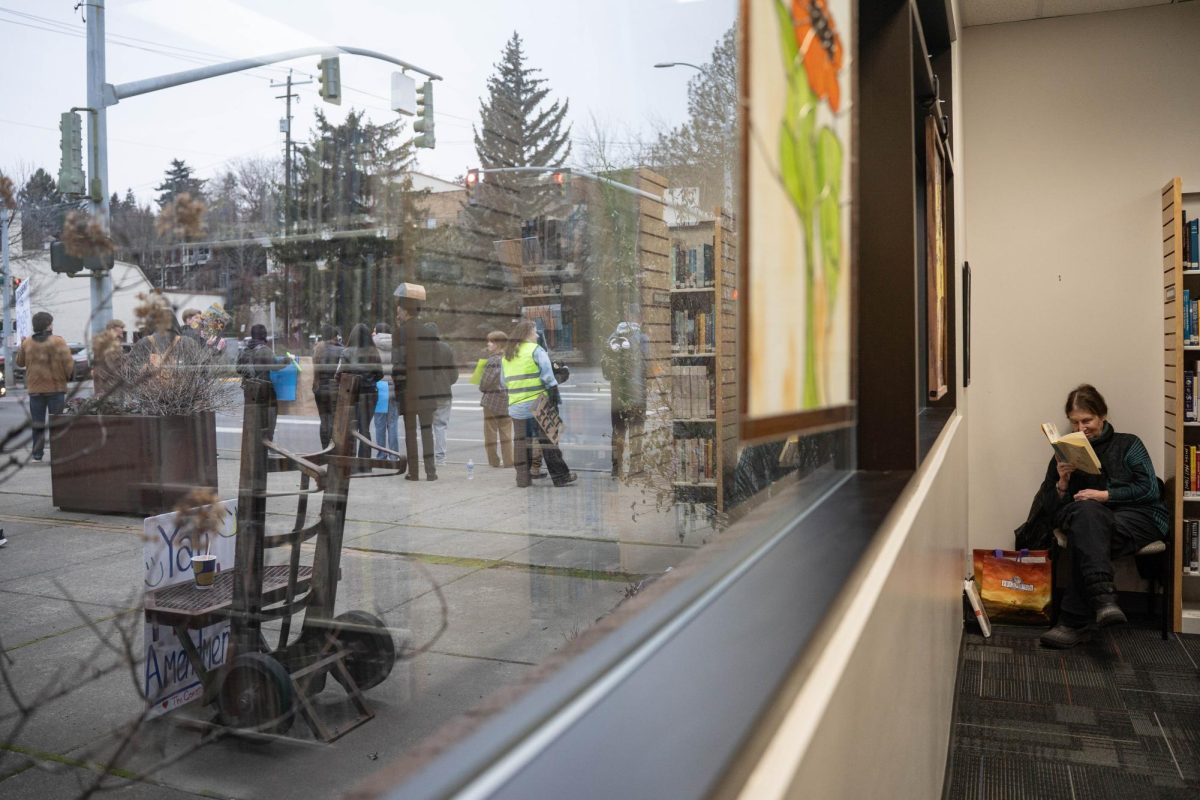 A woman reads her book as Anti-ICE Protesters chant outside the Pullman Public Libraby in downtown Pullman on Tuesday, Jan 20. 