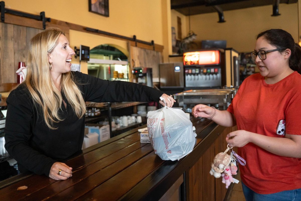 Manager Samantha Holt hands out a free meal during a "Feeding our Friends" event at Scusi Italian Restaurant in downtown Pullman on Tuesday, Apr. 14. 