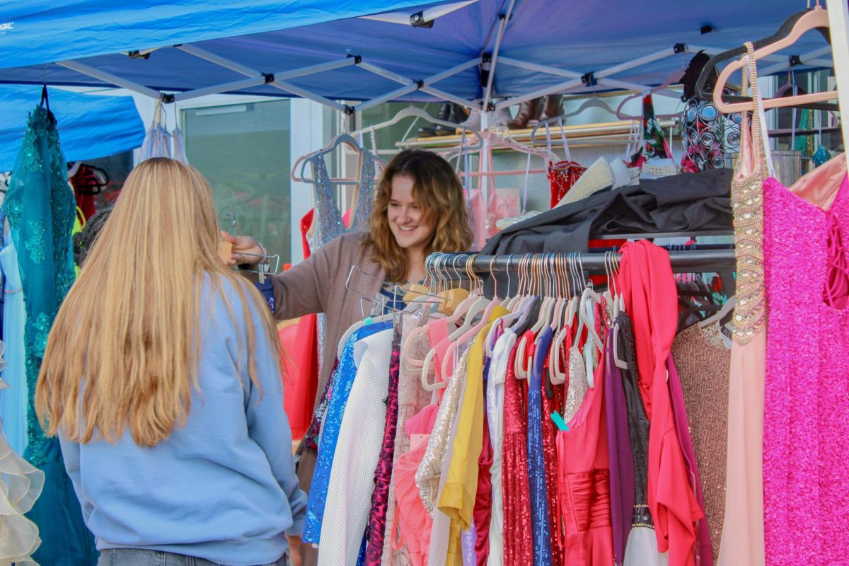 Customer showing a dress to a friend at Lily Bee's Boutique's closing sale, April 18, 2026.
