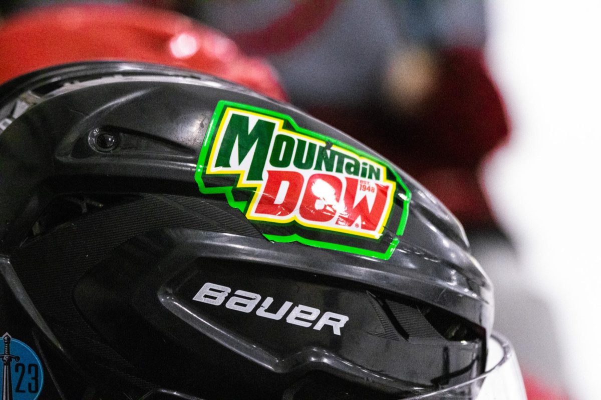 Joseph House's helmet glistening in the light during WSU hockey's 2026 prospect camp sitting on the bench wearing his Mountain Dew helmet. 