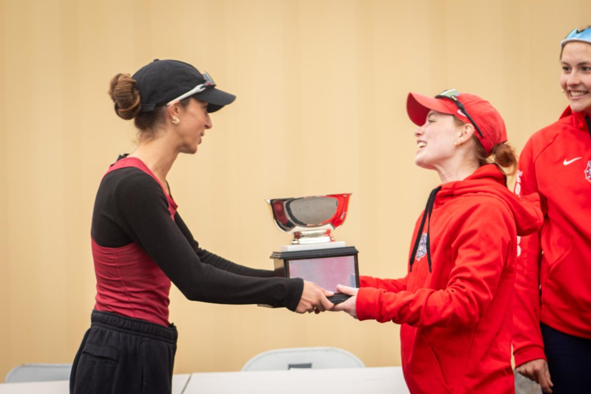 WSU coxswain Vera Lichvarcik (L) hands the Fawley Cup to Gonzaga coswain Ava Beekman (R) at Wawawai Landing on April 11.